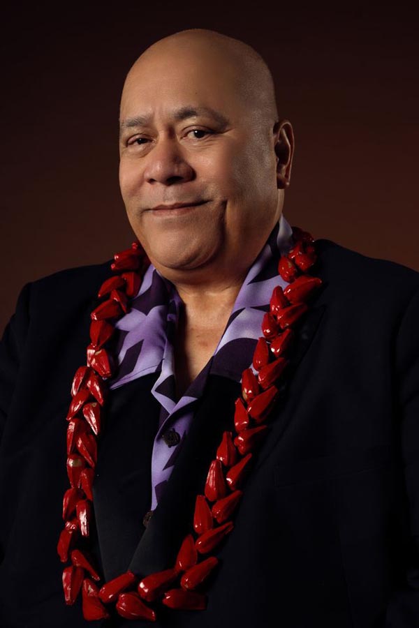 A smiling Pati Umaga wearing a red lei around his neck